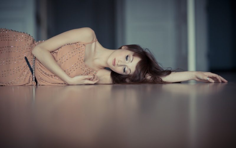 woman wearing pink dress lying on cement