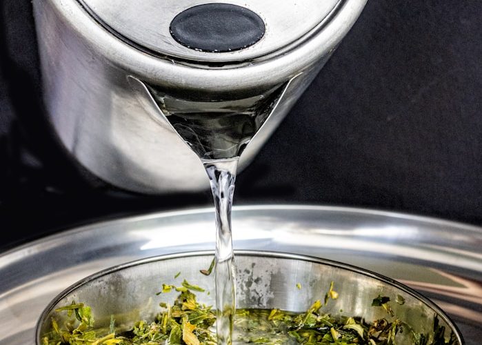 A silver bowl filled with green tea on top of a metal tray