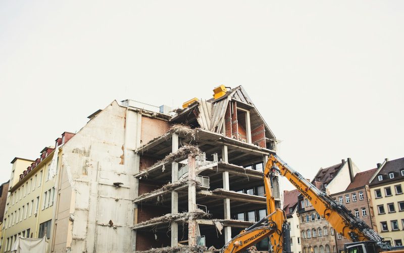 crane bull dozing a white concrete multi-storey building