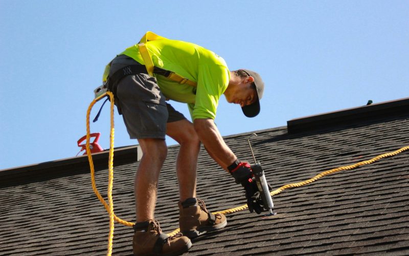 a man working on a roof with a power drill