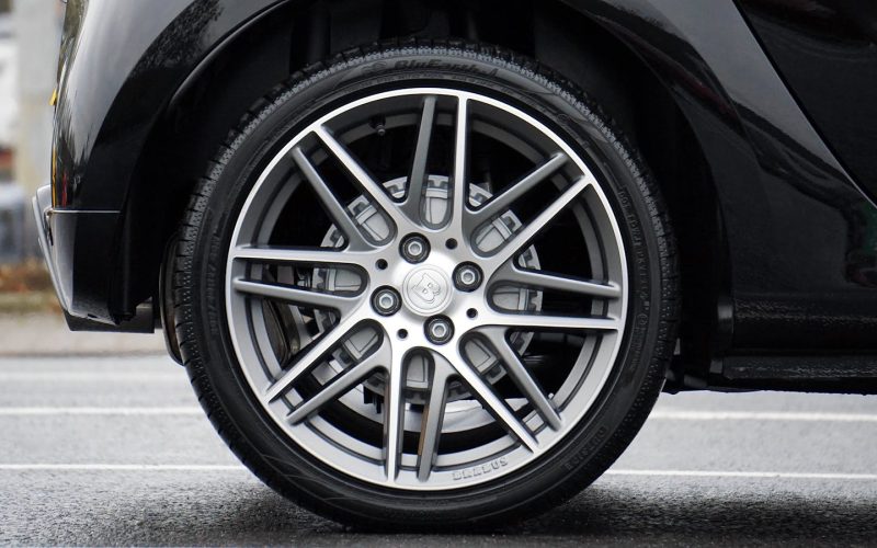 Detailed shot of a sleek car wheel and rim on a black vehicle, showcasing automotive design.