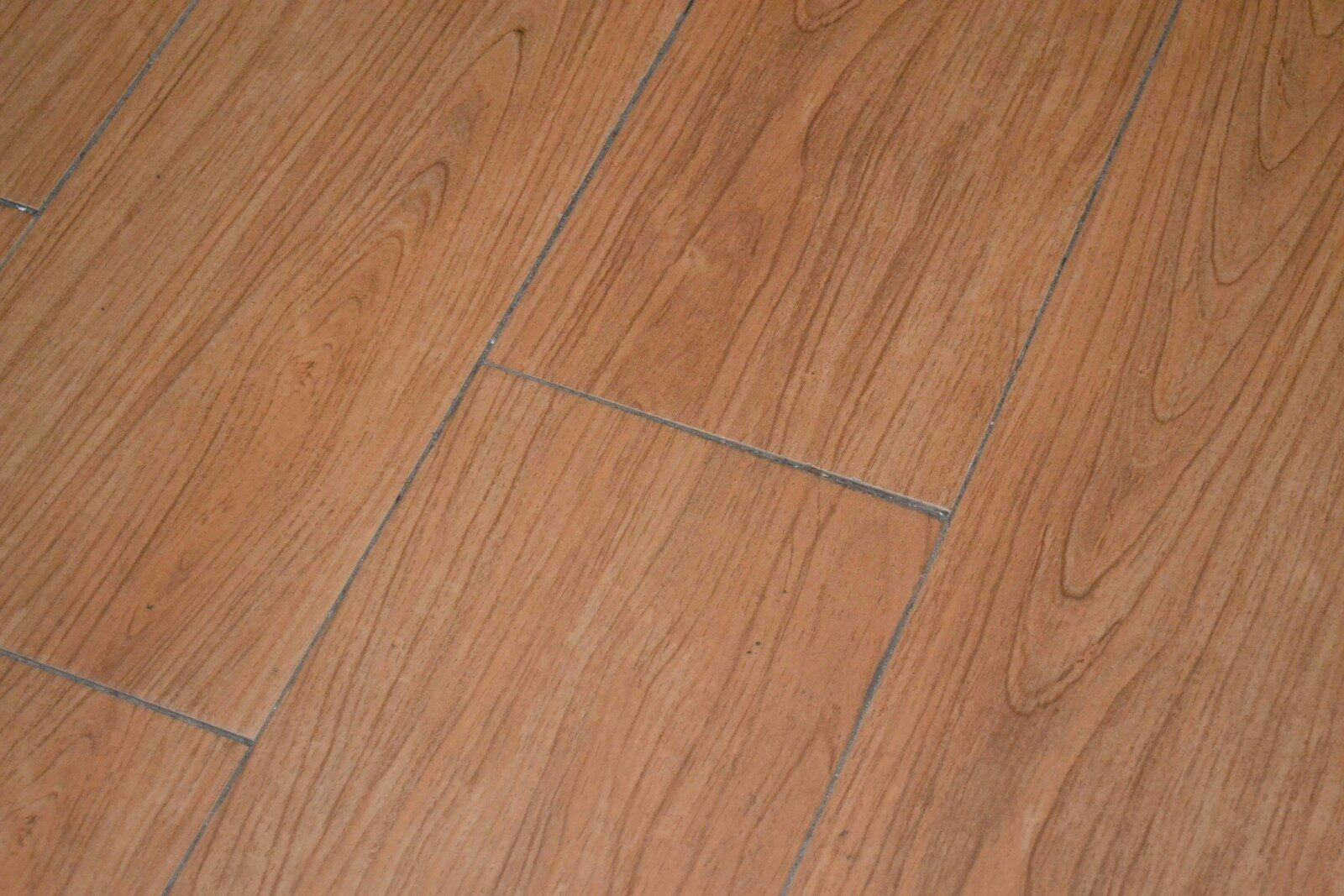 a close up of a wooden floor with a white cat laying on it